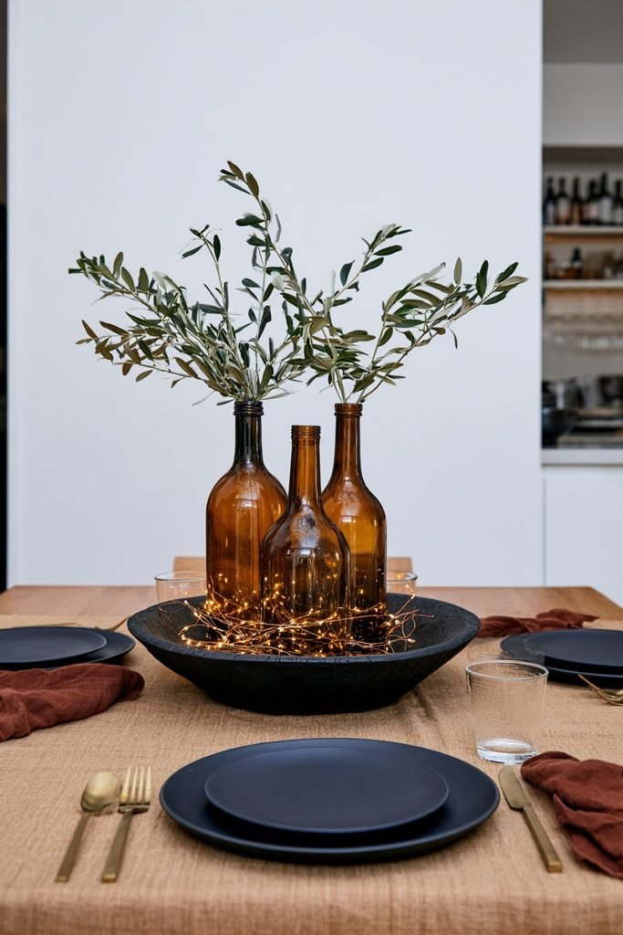 Sectioned reclaimed wood dough bowl filled with amber glass bottles, fall leaf garland, and warm fairy lights.