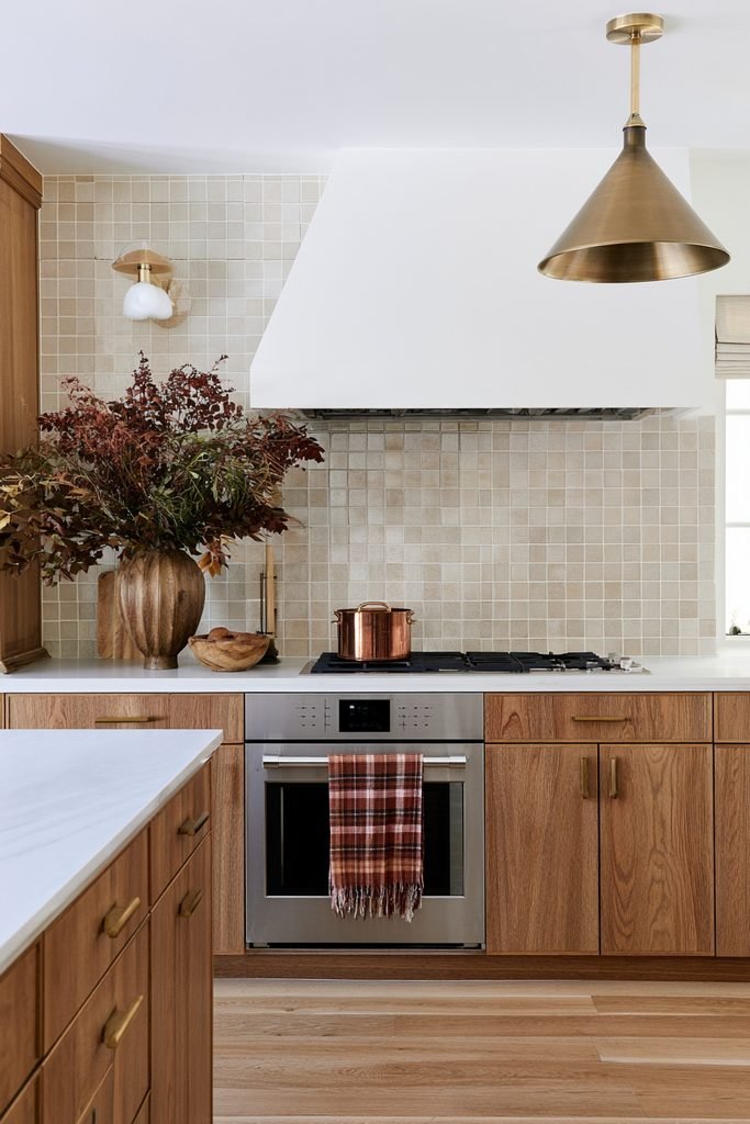 Rust plaid tea towel draped on an oven handle in a modern fall-styled kitchen