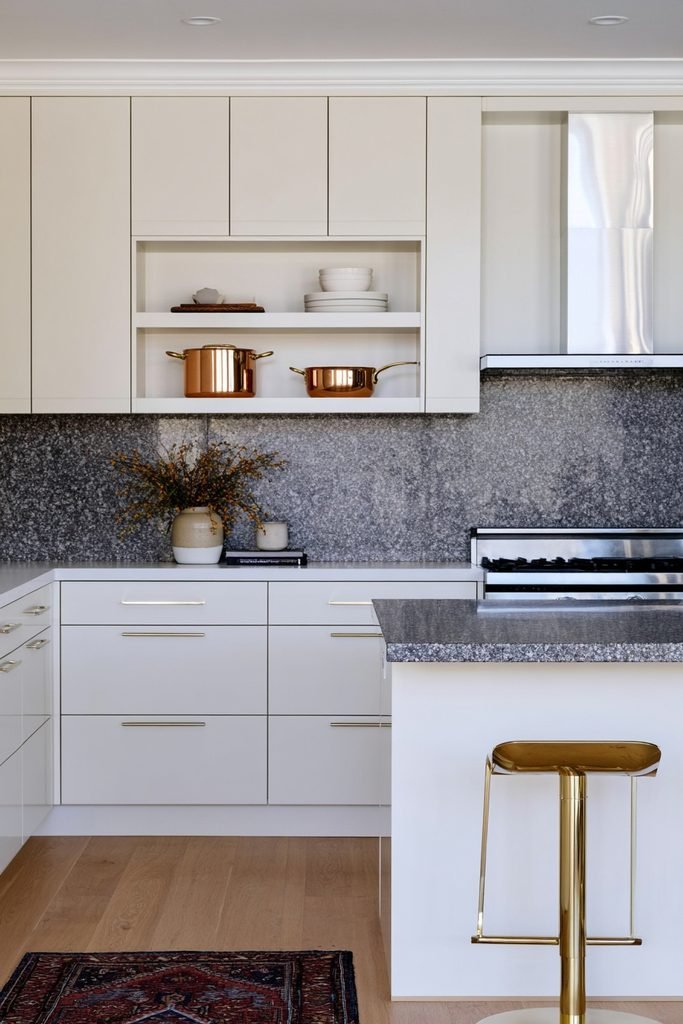 Polished copper pots and pans hanging in a modern dark and dramatic kitchen
