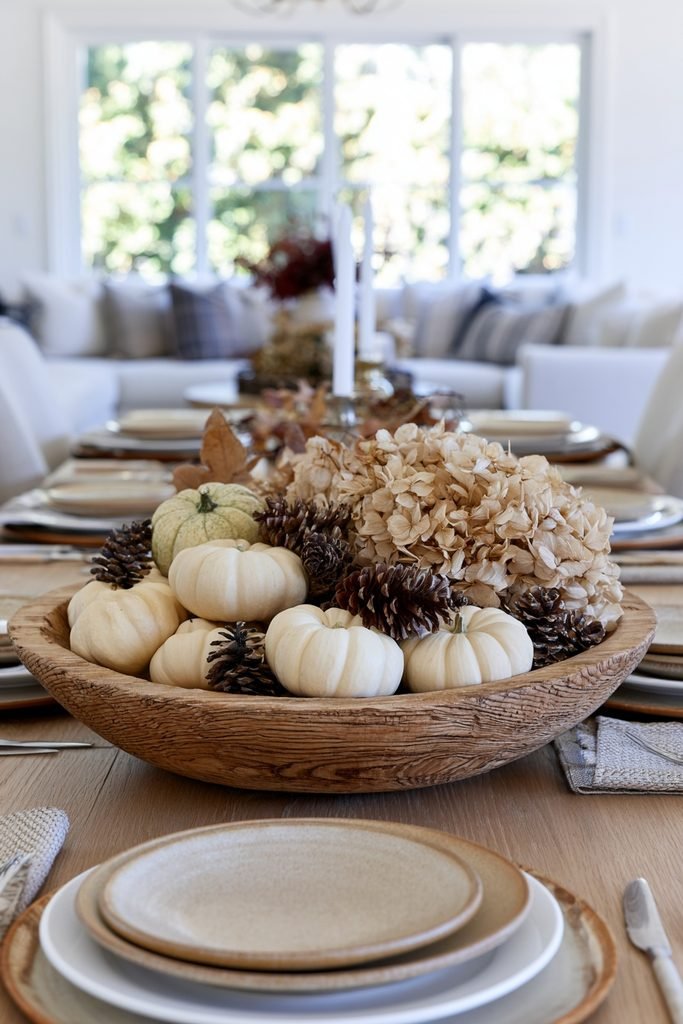 French country dough bowl filled with mini pumpkins, pinecones, and dried hydrangeas for a fall centerpiece.