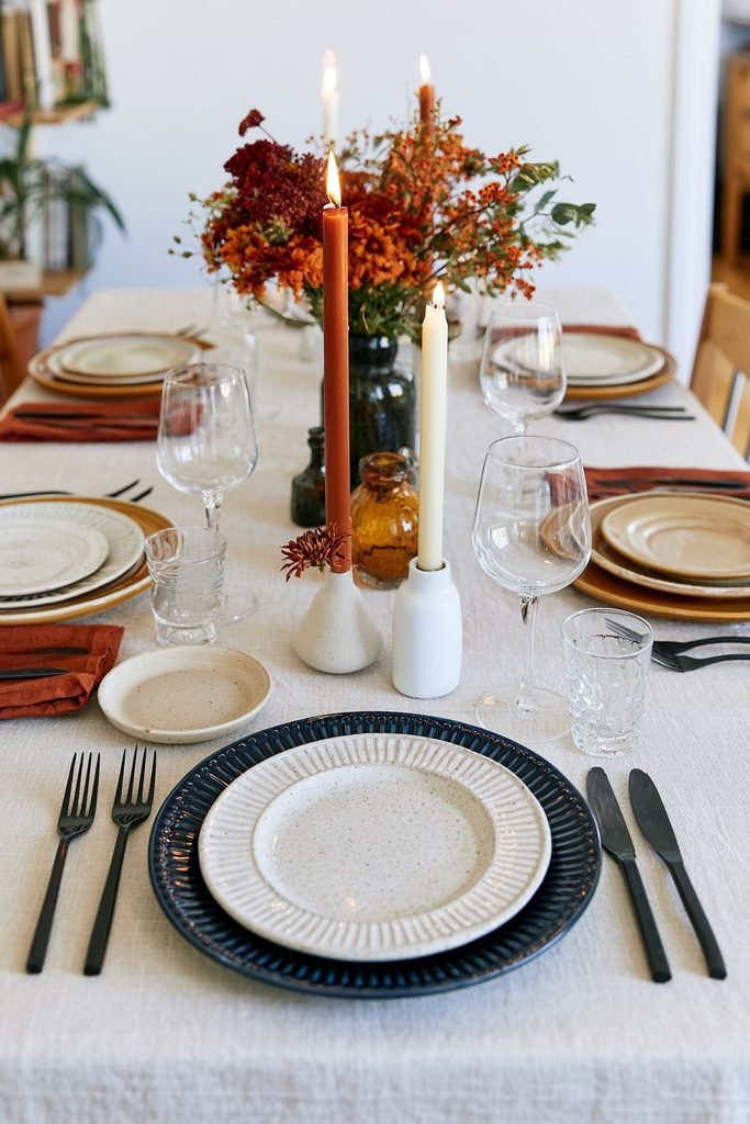 Budget-friendly fall dining table decorated with thrifted plates, vintage candle holders, repurposed vases and warm autumn accents.