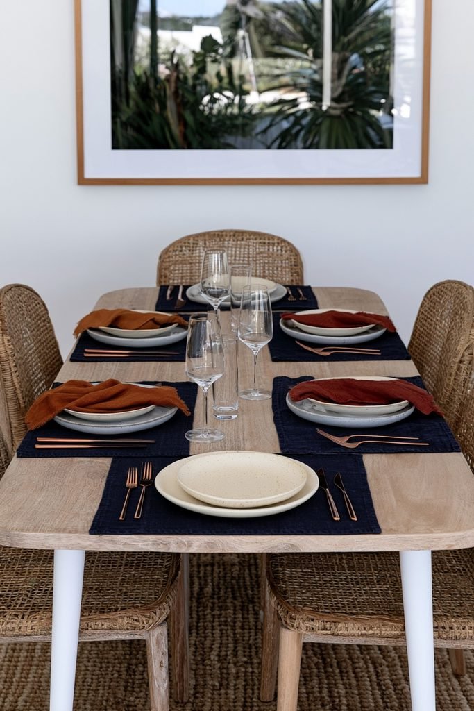 Dining table styled with burnt orange and terracotta linens against navy blue place mats
