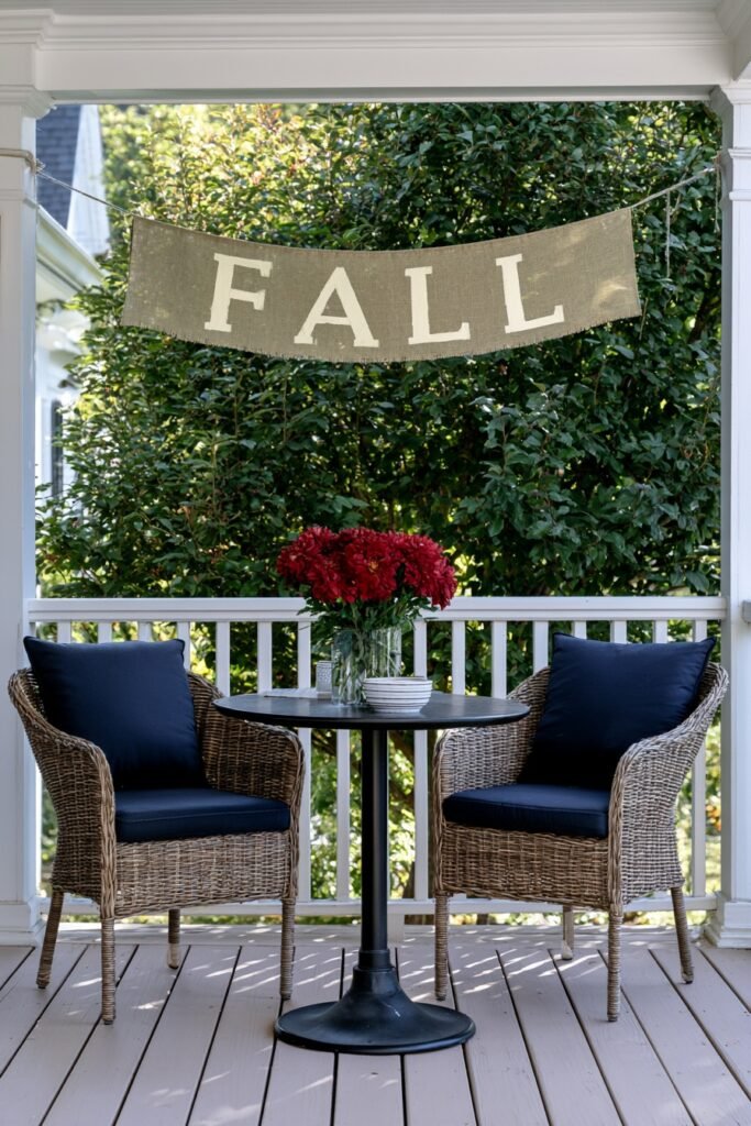 DIY burlap banner with stenciled fall lettering on a porch railing