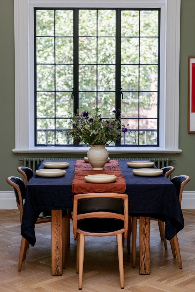 Navy tablecloth layered under a burnt orange linen runner on a wood dining table