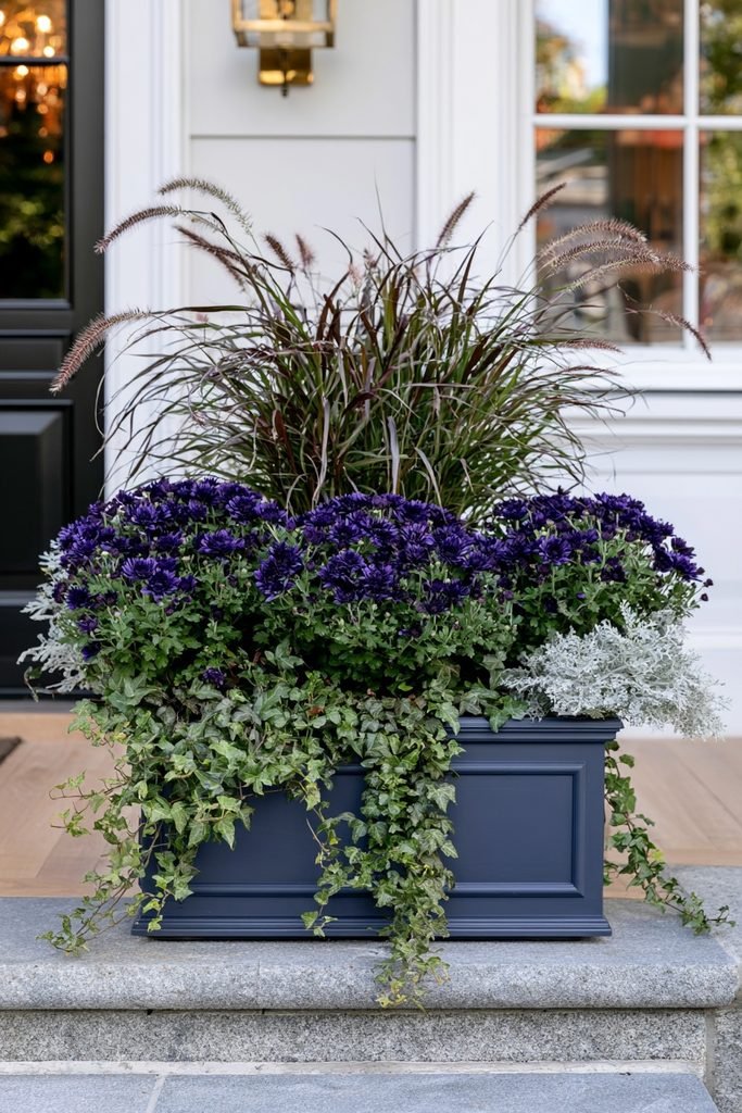 Purple fountain grass, chrysanthemums, and trailing ivy layered together in a beautiful fall planter