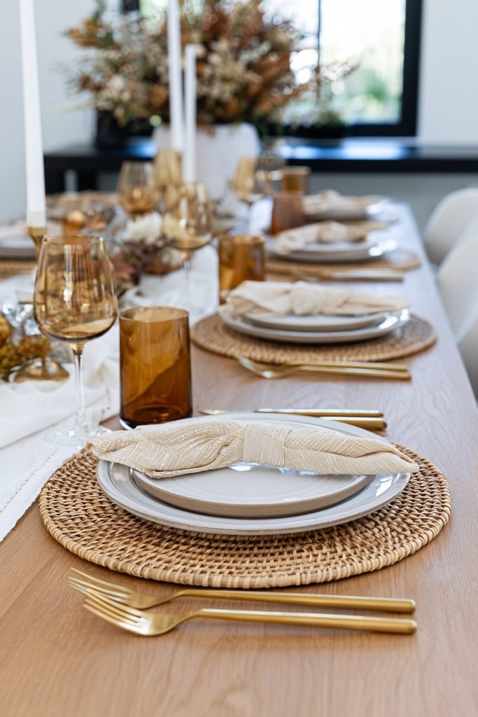 Fall place settings with layered ceramic dinner plates, natural rattan chargers, linen napkins and elegant gold cutlery.