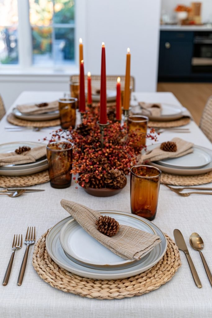 Warm earthy fall dining table decor with orange, red, yellow and brown accents, layered dinnerware and a seasonal centerpiece.