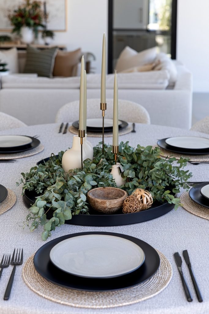 Modern black tray decorated with preserved eucalyptus branches, cream ceramic objects, and natural wood accents for fall