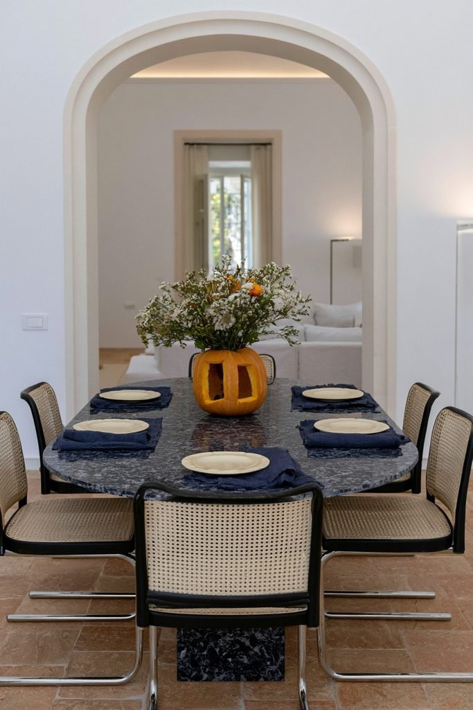 Hollowed-out orange pumpkin used as a vase with white and orange blooms