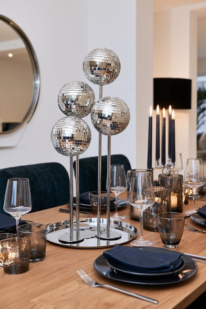 New Year's Eve dining table decorated with mirrored disco balls and chrome accents