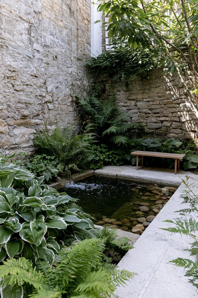 Modern house courtyard with a small water feature surrounded by plants and patio seating