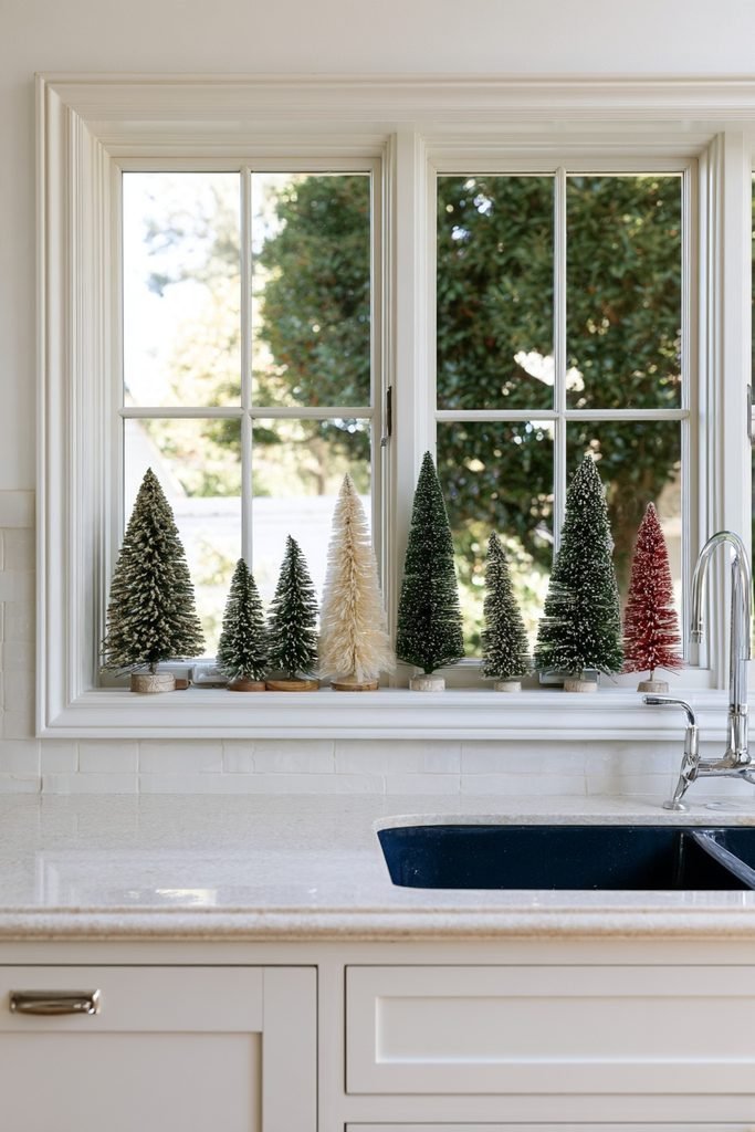 Mini bottle brush Christmas trees arranged along a kitchen windowsill