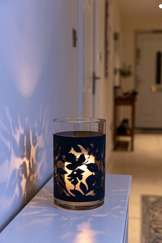 DIY leaf silhouette candle luminaries casting warm autumn patterns in a cozy hallway at night.