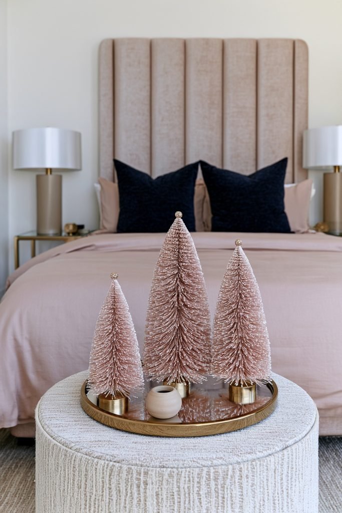 Trio of small pink bottlebrush Christmas trees arranged on a bedroom nightstand