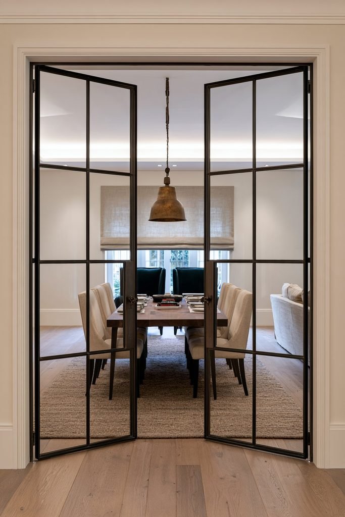 Elegant dining room with symmetrical French-style Crittall glass doors connecting to a sitting room