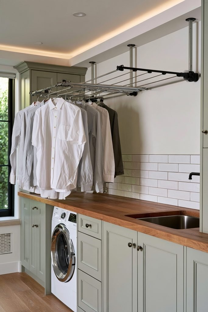Wall-mounted fold-down drying rack above a countertop in a bright Scandinavian utility room