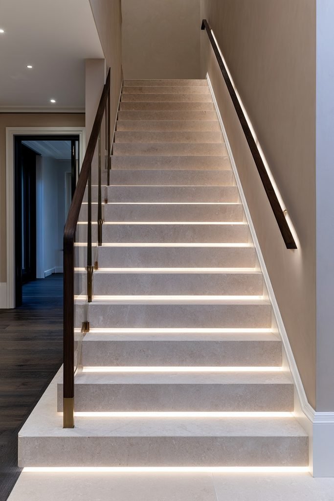 Modern staircase featuring concealed lighting beneath a wide wooden handrail
