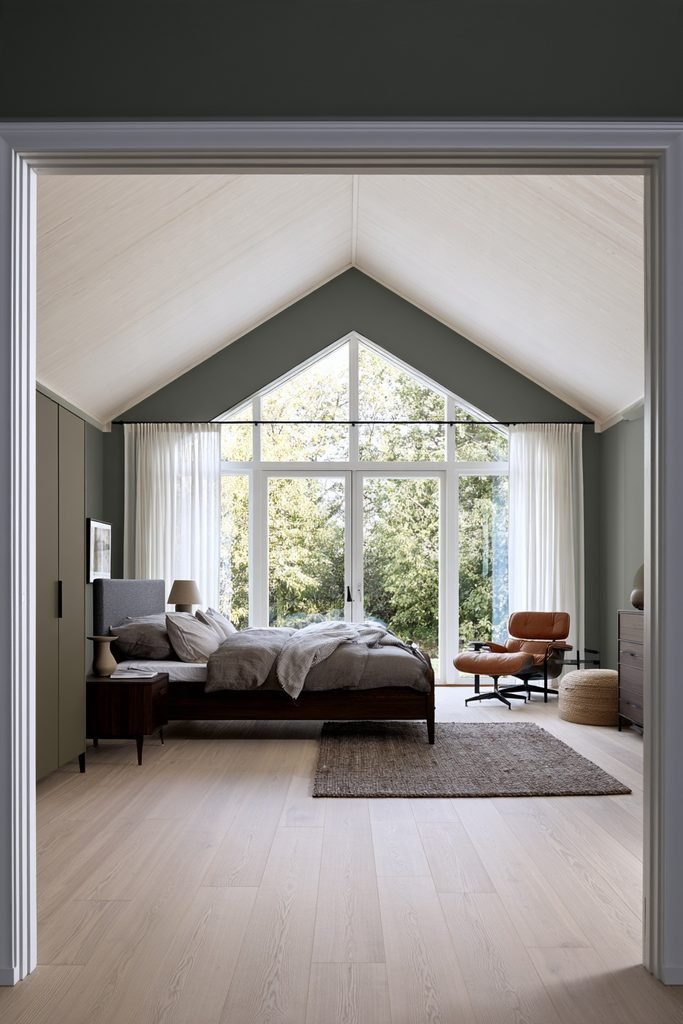 Scandinavian bedroom with sheer white linen curtains, dusty blue walls, oak bed, and bright natural light