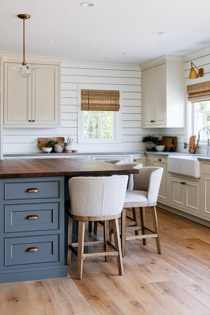 White horizontal shiplap accent wall in a traditional farmhouse kitchen with cream cabinets, walnut island, blue-gray accents, and brass lighting.