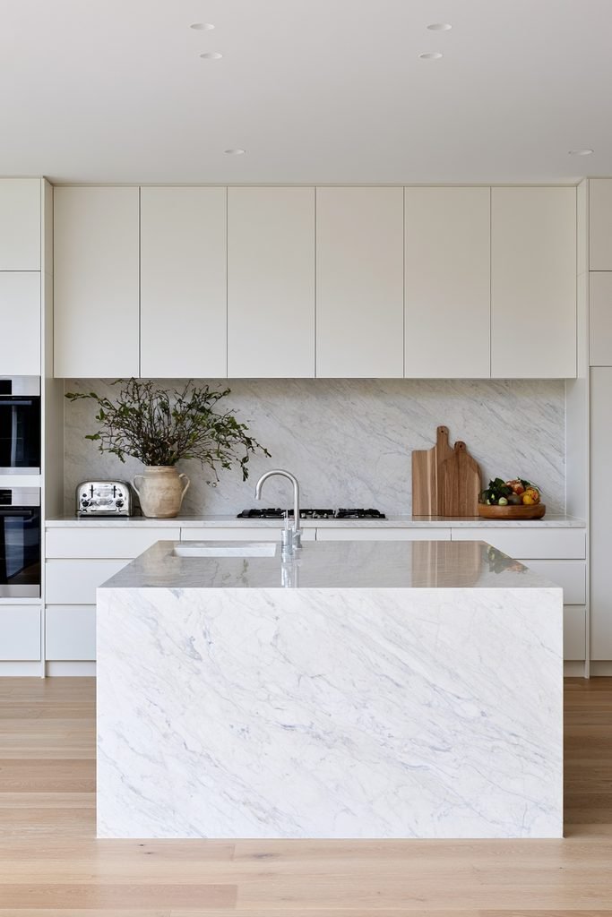 Modern kitchen with a continuous stone slab countertop and matching full-height backsplash.