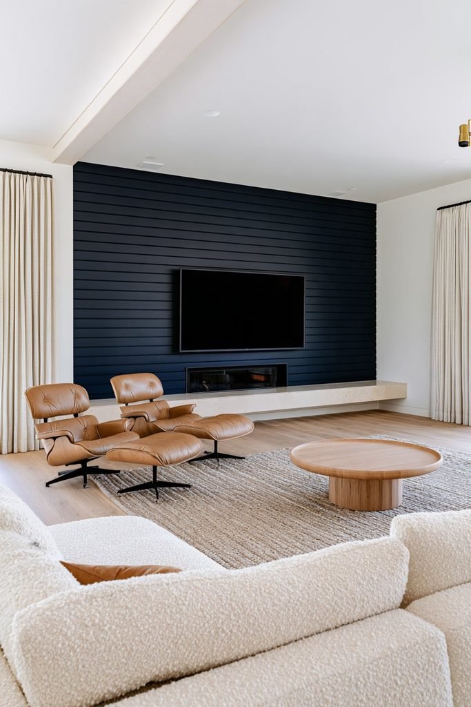Navy blue shiplap fireplace wall with a mounted TV, cream stone hearth, neutral sofa, leather chairs, and oak flooring.