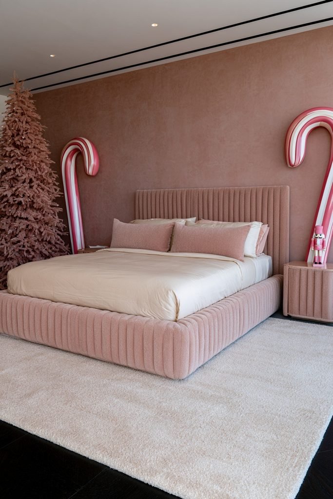 Oversized pink and white candy cane decorations framing a festive Christmas bedroom
