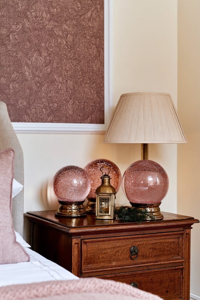 Collection of pink Christmas snow globes arranged on a bedroom nightstand