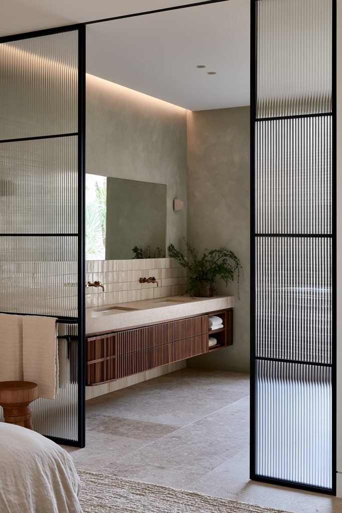Modern ensuite bathroom with a black Crittall door featuring privacy ribbed glass and a walnut vanity