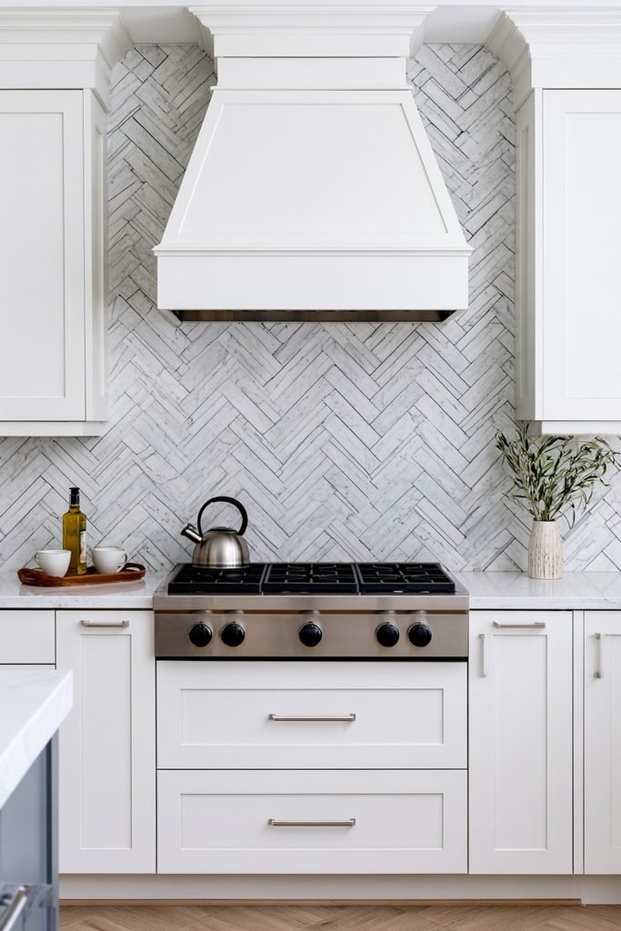 Luxury kitchen featuring a marble chevron backsplash with dramatic veining and a modern styled countertop.