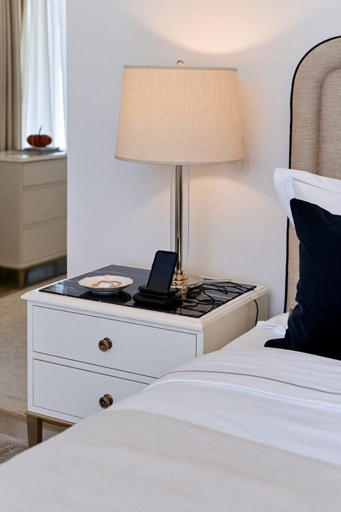 Thanksgiving guest bedroom bedside table with a lamp, jewelry dish, eyeglass space, and phone charging area.