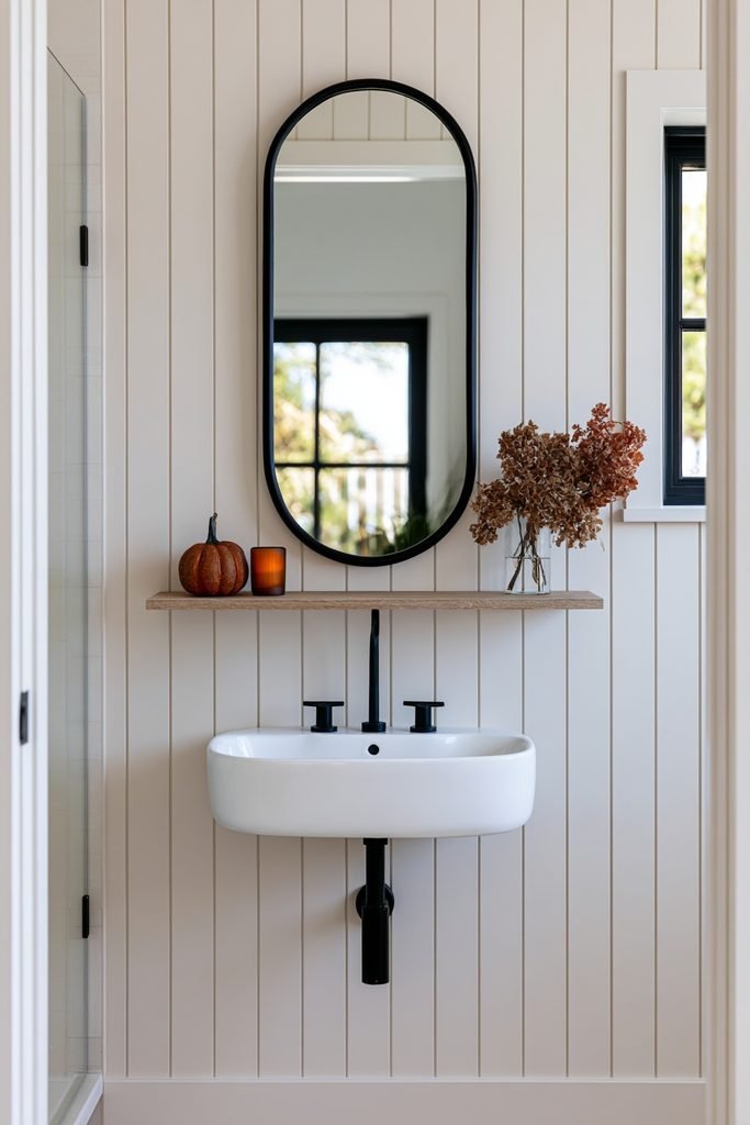 Small bathroom with a floating wood shelf styled with subtle fall decor