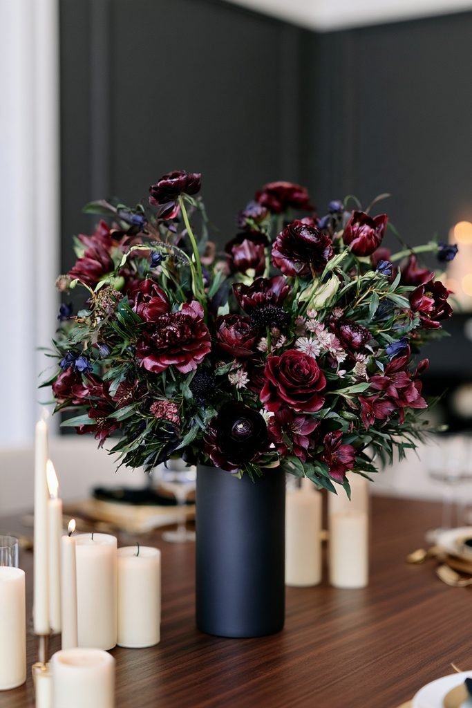 New Year's Eve dining table decorated with burgundy, ruby, emerald, and sapphire jewel-tone flowers