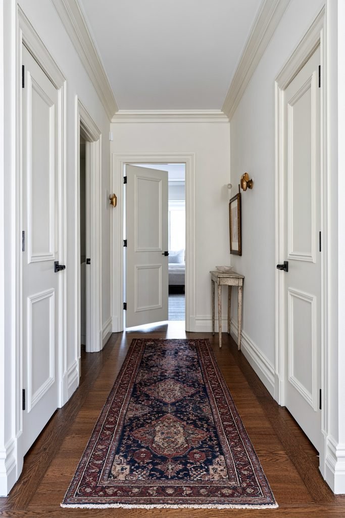 Vintage Persian hallway runner in a traditional entry foyer with an oak front door, console table, oval mirror, bench, baskets, and plants.