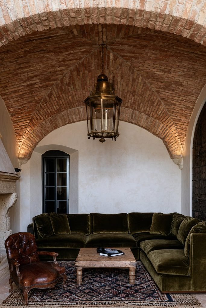 Aged red brick vaulted statement ceiling with antique brass lantern in a characterful European interior