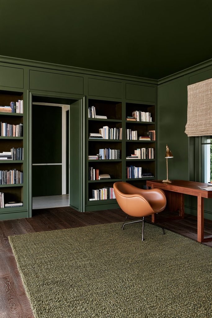 Deep green colour-drenched reading room with matching built-in shelves, walls, ceiling, walnut desk and leather chair