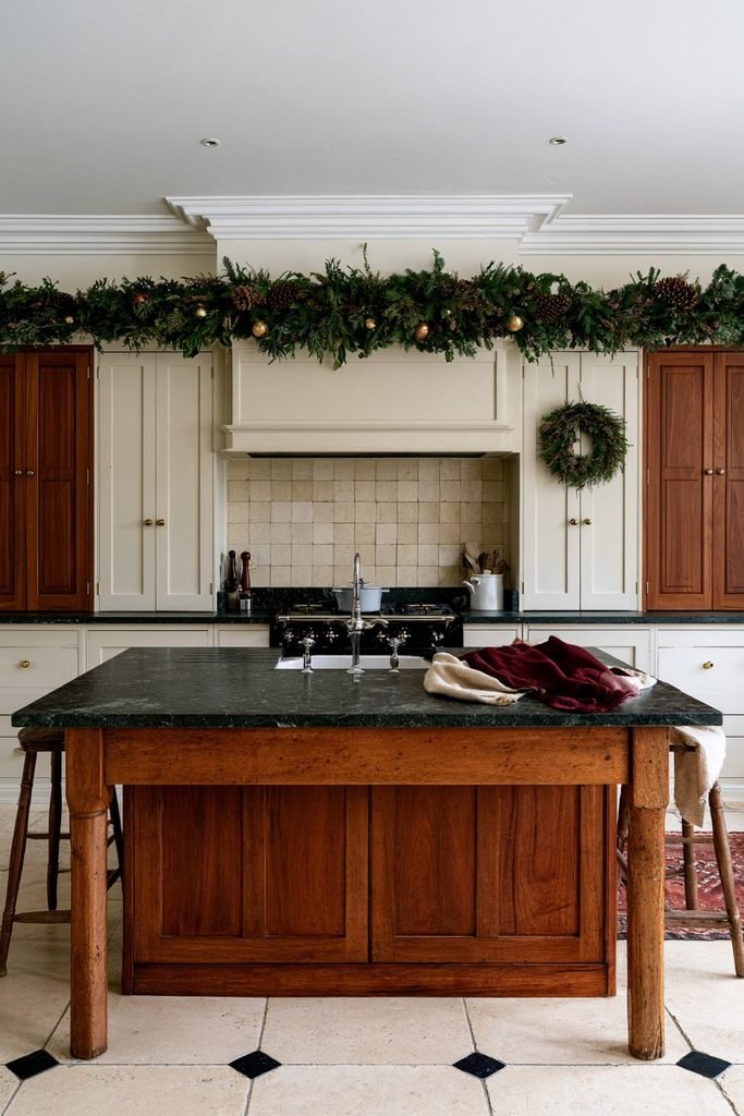 Evergreen Christmas garland decorating the top of kitchen cabinets in a cozy holiday kitchen