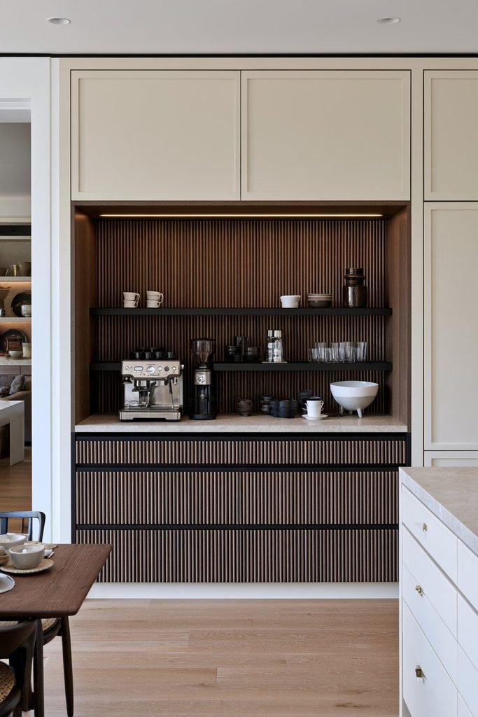 Custom kitchen coffee station with a walnut fluted niche, integrated coffee appliances, black shelving, stone countertop, and surrounding built-in cabinetry.