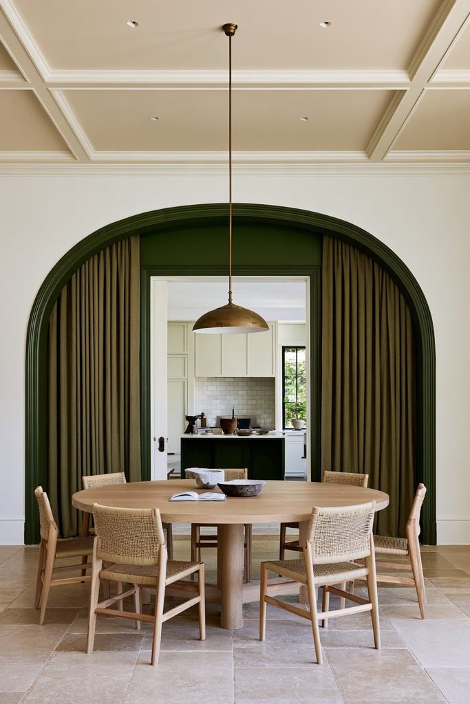 Forest green arched doorway casing contrasting with warm white walls in a dining room.