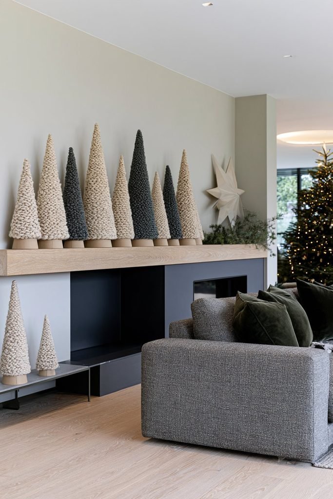 DIY Scandinavian Christmas cone trees wrapped in cream, sage, and charcoal yarn arranged on a fireplace mantel.