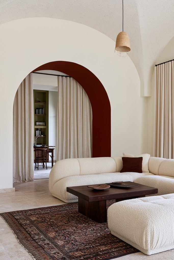 Rounded arched doorway with a contrasting terracotta-painted inner reveal in a modern living room.