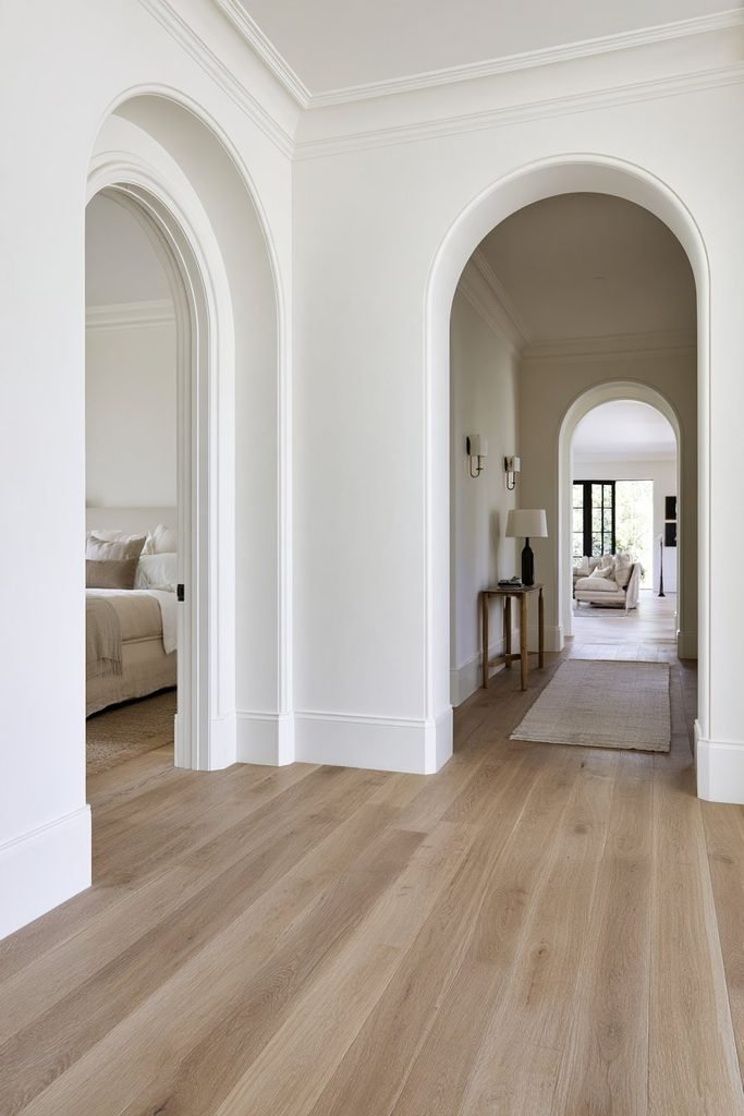 Repeated warm-white arched doorways creating a stylish rhythm in a residential home hallway.