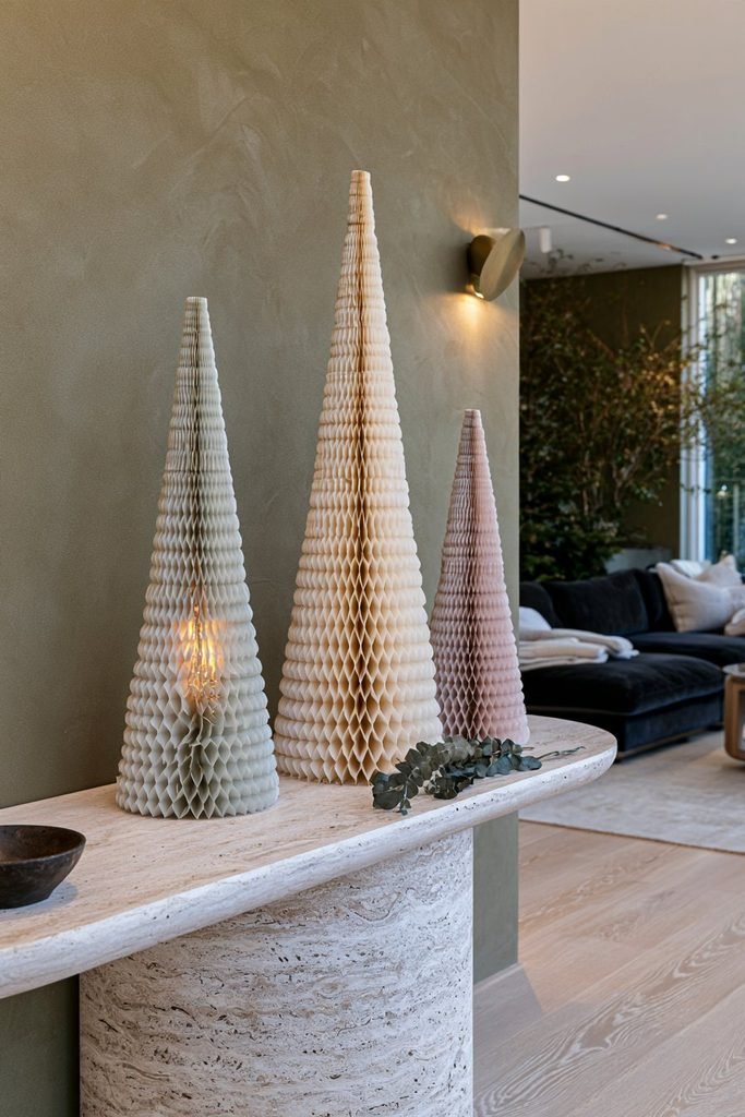 DIY honeycomb tissue paper Christmas trees in sage green, cream, and dusty blush displayed on a modern console.