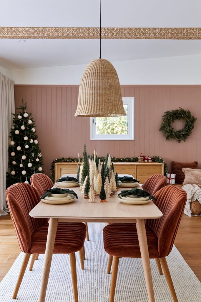 Christmas dining table decor with miniature Christmas trees arranged across a square pale terrazzo table, colorful upholstered chairs, and a festive dining room.