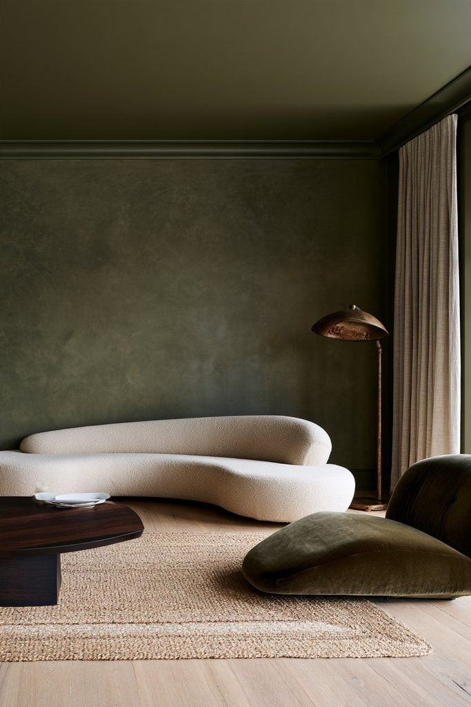 Olive green colour-drenched living room with limewashed walls, matte ceiling, satin trim and layered natural textures