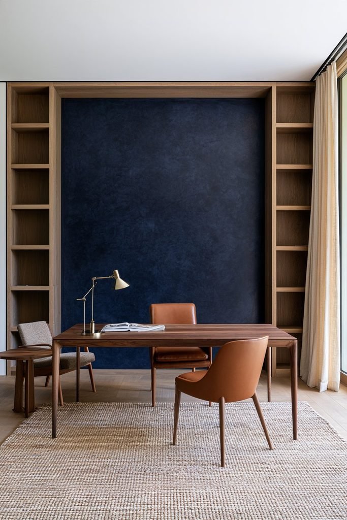 Deep navy Venetian plaster home office wall with an oak desk, leather chair, and brass task lighting