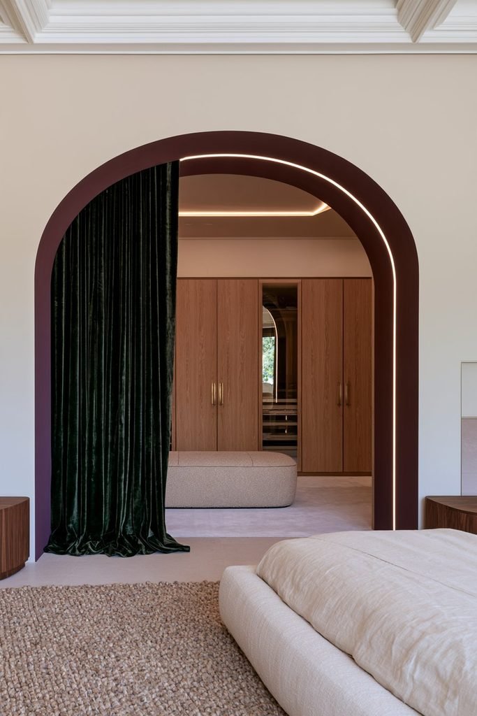 Arched entrance leading to a boutique-style walk-in closet with a velvet curtain and LED lighting.