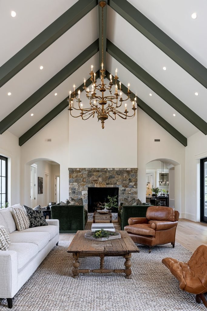 Deep green painted beam statement ceiling with brass chandelier in an elegant contemporary living room