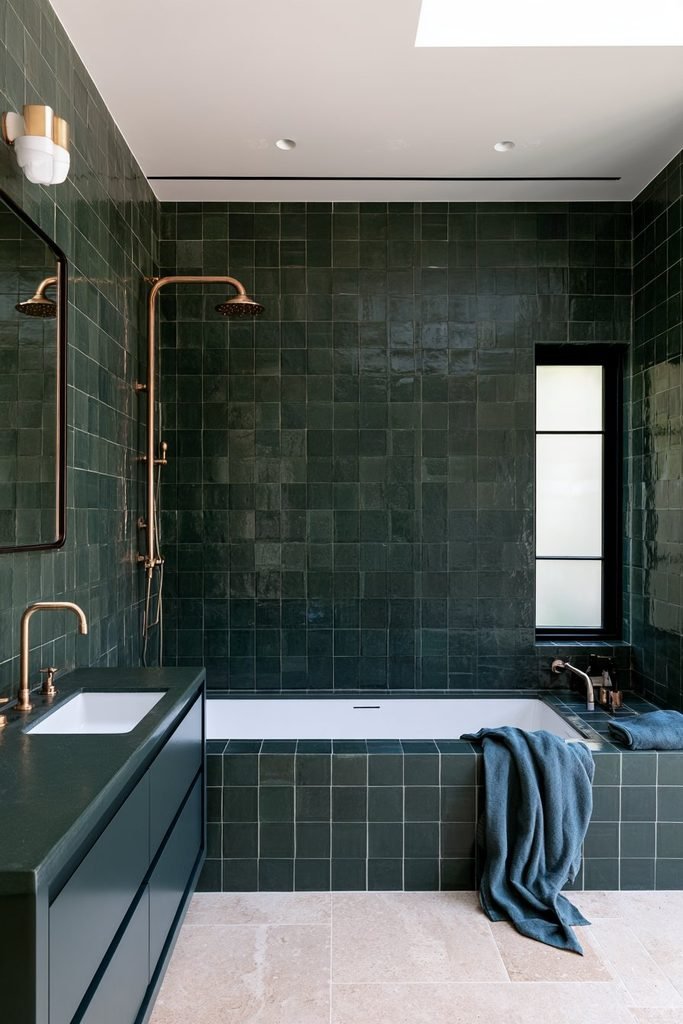 Deep blue-green colour-drenched small bathroom with textured wall tiles, matching ceiling, vanity and brass fixtures