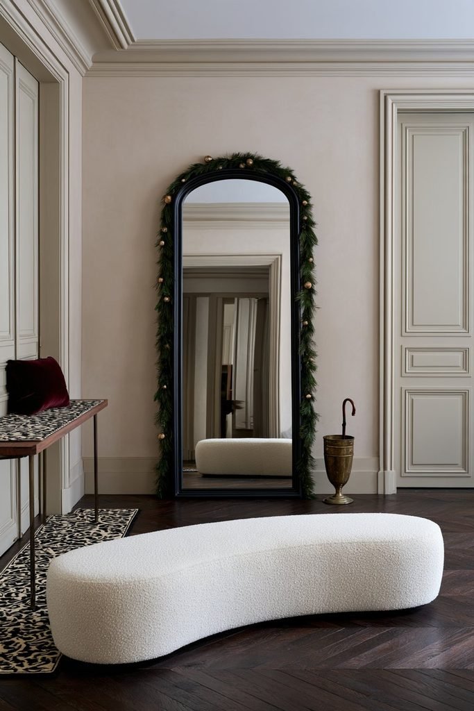 Evergreen Christmas garland decorating a large standing mirror in a Christmas-themed room