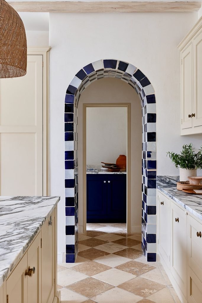Blue handmade ceramic tiles lining the inner reveal of an arched kitchen doorway.